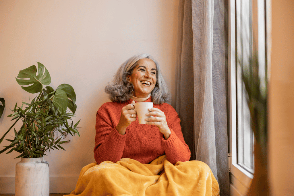 A happy woman enjoying her retirement with a cup of coffee at home